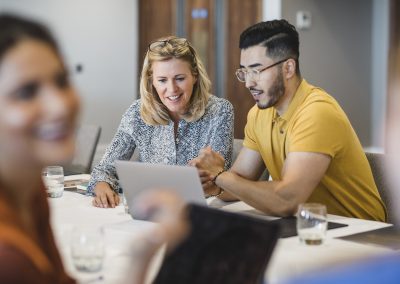 Hipster young man showing female colleague laptop